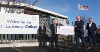 four men holding sign in front of St Laurence College - fujitsu strategic community investment